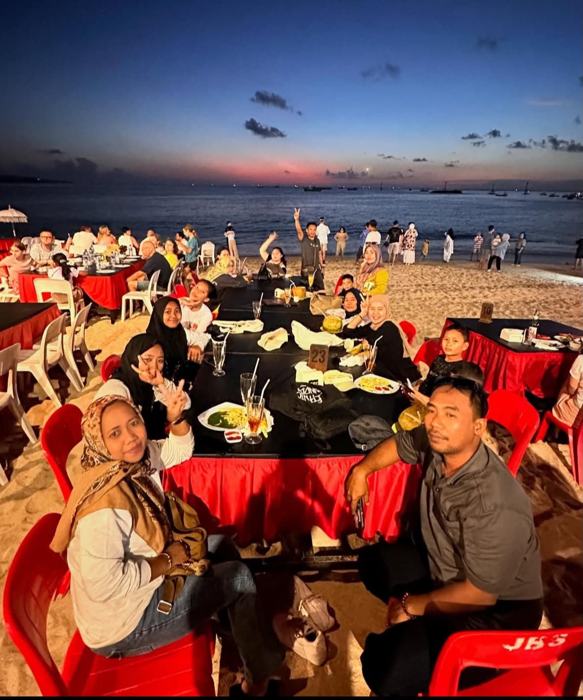 Group enjoying a beachfront sunset dinner